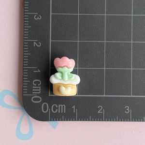 Macro shot of mini resin pink flower accessory on a measuring mat showing size details