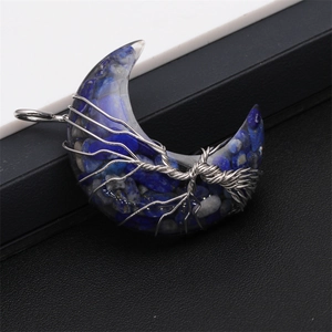 Close-up of crescent moon pendant with blue lapis stones and silver tree of life wire wrap