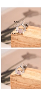 Detailed view of silver fishtail stud earrings with pink gemstone and zircon accents