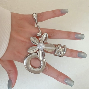 Detailed view of silver flower ring set with pearl inlay and wide textured band on hand