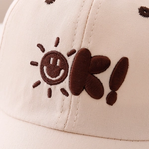 Kids baseball cap featuring sun embroidery and OK text in soft beige cotton fabric