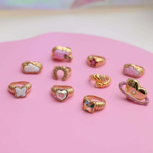Artistic gold-plated rings with opal heart and butterfly designs on pink surface
