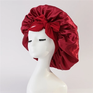 Detailed view of dark red satin sleep bonnet with bow tie on a mannequin head