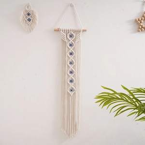 Detailed close-up of woven cotton tassels and blue evil eye beads on boho wall hanging