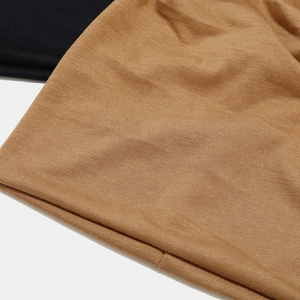 Gros plan sur la texture en tricot noir et caramel de ces bonnets légers et souples