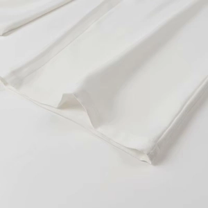 Close-up of white fabric texture showing detailed stitching on the suit sleeve cuff