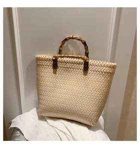 Detail of minimalist beige woven tote bag featuring natural bamboo handles and textured finish