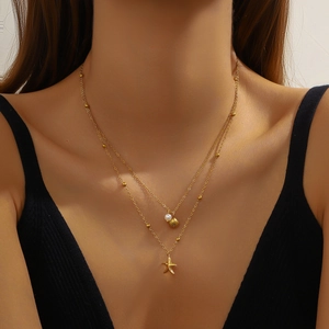 Gold double layer necklace with pearl, shell and starfish pendants on a model