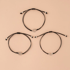 Detailed flat lay of three adjustable black woven bracelets with sun, moon, and star pendants