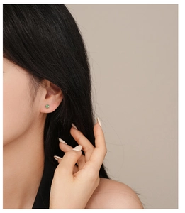 Close-up of a mini green zircon flower stud earring worn by a model in silver