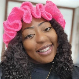 Macro shot of bright pink ruffled knitted headband with chunky yarn texture on model