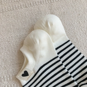 Close-up of striped ankle socks with small heart embroidery on a fabric background