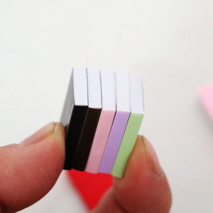 Five colorful 1:12 scale dollhouse miniature books held between fingers for BJD decor