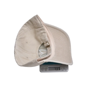 Beige Baumwoll-Baseballkappe mit Herzstickerei, wiegt 73,7 g auf einer Digitalwaage
