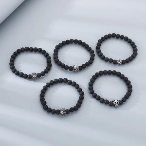 Detail of five black lava rock skull bracelets with vintage silver metal bead charms