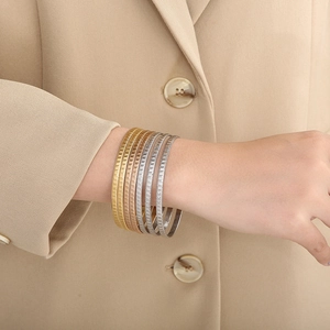 Dettaglio di bracciali a strati in acciaio al titanio con texture martellata su una modella