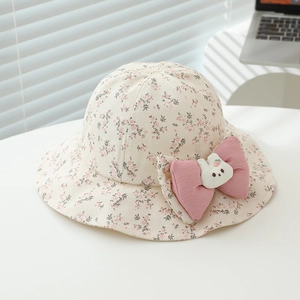 Close-up of floral baby sun hat with large pink bow and cute strawberry rabbit doll