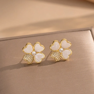 Elegant four-leaf clover stud earrings with white pearl shell and zircon on a jewelry box