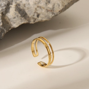 Detailed view of a golden bamboo-shaped open ring placed on a rustic stone background