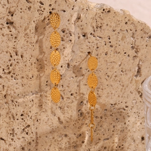 Vue détaillée de longues boucles d'oreilles dorées avec disques ovales martelés texturés