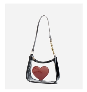 Detail of PVC crossbody bag showing red heart logo and black patent leather texture