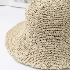 Close-up of beige wide brim straw hat showing intricate handmade crochet texture and weave