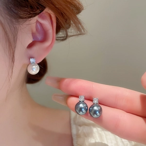 Detail of high-luster pearl earrings with rhinestones in white and grey-blue tones