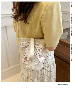 Detail of straw woven bucket bag featuring floral silk scarf and metal chain strap