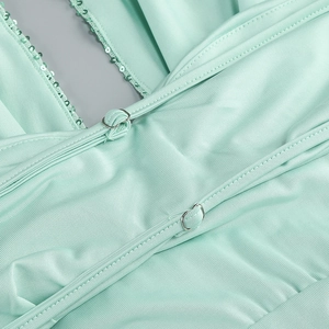 Detailed macro of mint green ribbed fabric with sequins and metallic ring fastener