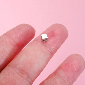 Polished 4mm mirror stainless steel square bead displayed on a fingertip