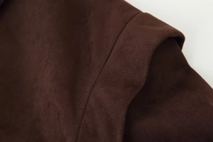 Macro detail of dark brown suede fabric texture and premium stitching on lapel jacket