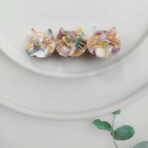 Detail of three-headed marble pattern acetate cat hair clip on a white plate