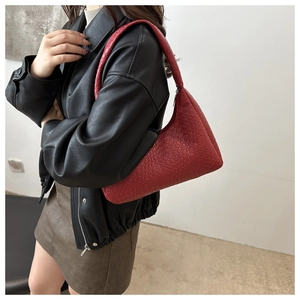 Detail of red woven texture on faux leather underarm bag held by female model