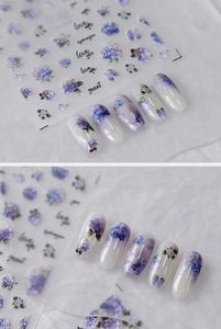 Macro detail of watercolor hydrangea nail stickers with blue and purple floral designs
