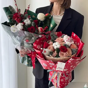 Christmas bouquet with red roses and pine needles wrapped in snowflake pattern paper
