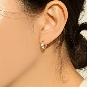 Minimalist silver hoop earrings with white pearl detail on female model's ear lobe