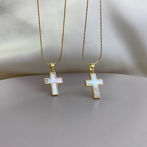 Detailed macro view of two golden cross pendants featuring natural mother of pearl inlay