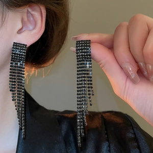 Détail de boucles d'oreilles longues à pampilles en strass noirs au design élégant