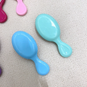 Detailed close-up of mini colorful hairbrushes on a beige fabric background