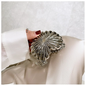 Close-up of heart-shaped silver metal evening bag with textured surface and chain