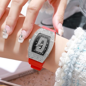 Macro view of tonneau shaped watch with sparkling rhinestones and red silicone strap