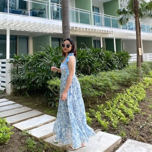 Detail of blue floral maxi dress featuring bow shoulder straps and tiered skirt design