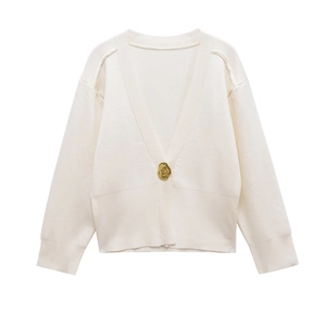 Detail of white V-neck knit cardigan featuring a unique gold abstract button and ribbed cuffs