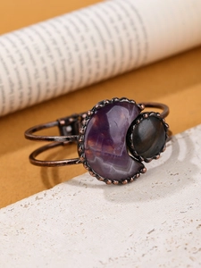 Macro shot of a vintage bronze bracelet with a purple crescent moon and grey gemstone