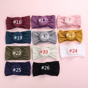 Flat lay of 11 colors of soft ribbed knit baby headbands with donut knot details