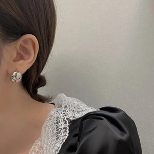 Primo piano di eleganti orecchini a lobo in argento lucido indossati da una modella chic
