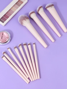 Macro shot of 13 professional pink makeup brushes with soft gradient bristles on purple backdrop