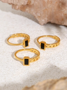 Detailed shot of golden minimalist rings with black shell inlay on a stone background