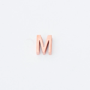 Macro-opname van een 3D-letter M kraal in roségoud met een gepolijste spiegelafwerking