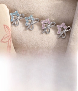 Macro shot of silver bow and star cartilage piercings with blue and pink zircons